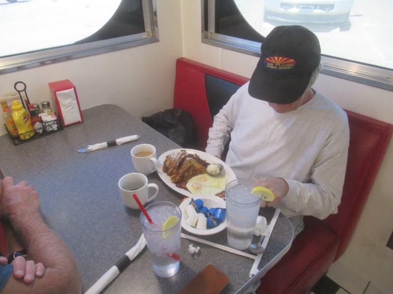 John is putting the finishing touches on his breakfast because he thinks it is rude to start eating 
